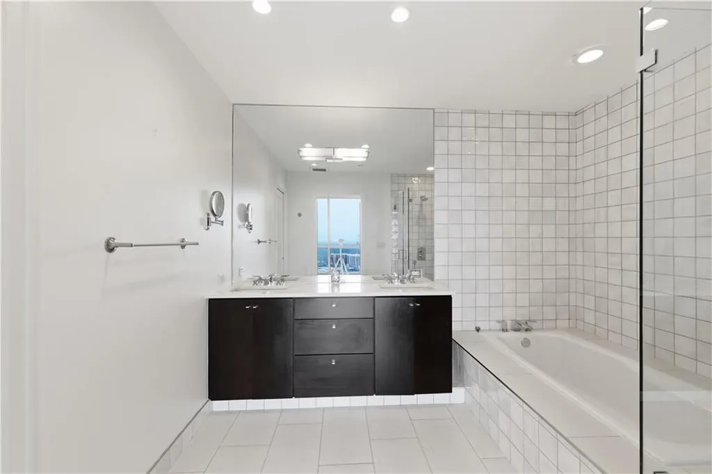 Dual vanity with dark wood-finish cabinetry, integrated rectangular sinks, and an oversized mirror
