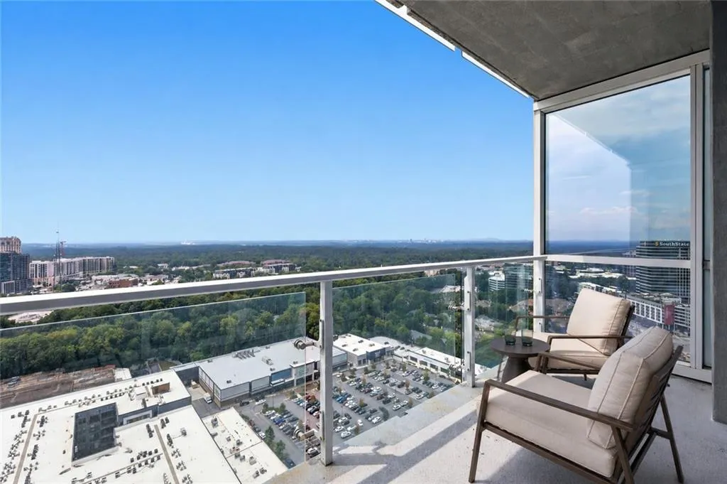 VIRTUALLY STAGED-Private balcony with glass railing, concrete flooring, and sliding glass doors