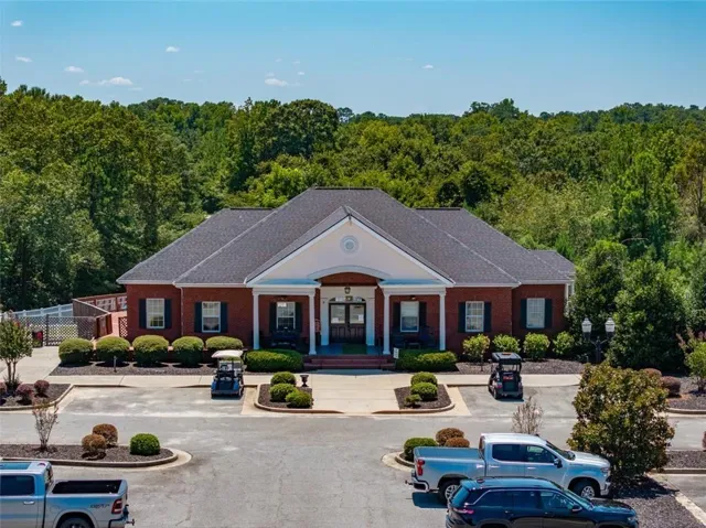 View of building exterior with uncovered parking and a forest view