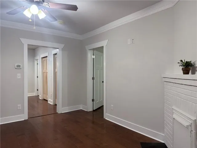 Unfurnished bedroom featuring ornamental molding, dark wood finished floors, and a ceiling fan