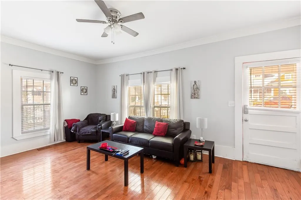 Living room with ceiling fan, ornamental molding, and plenty of natural light
