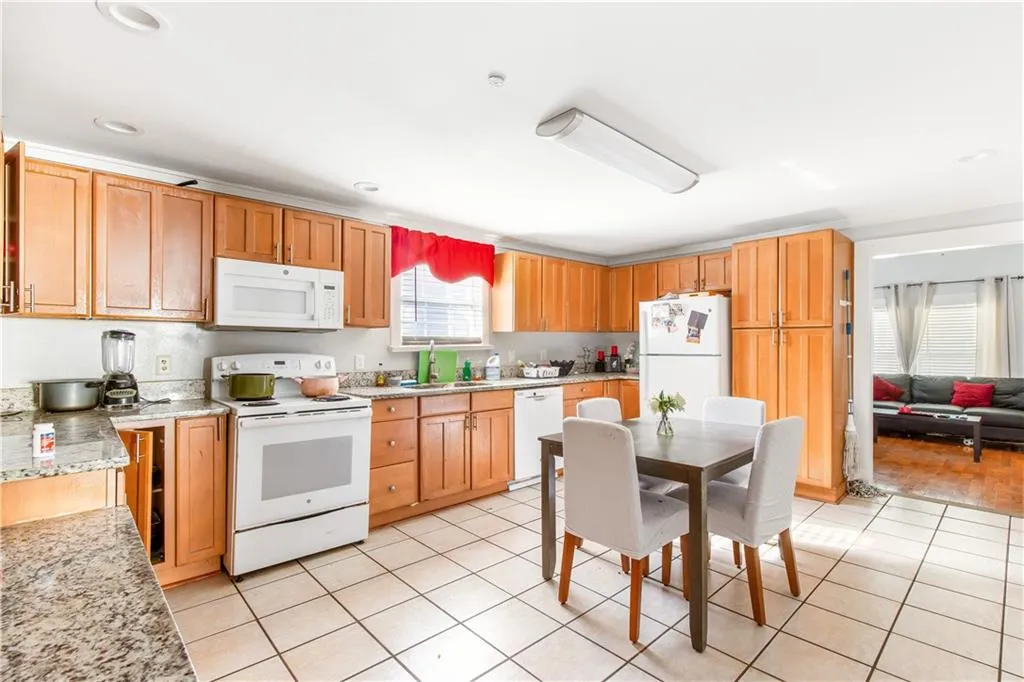 Kitchen featuring sink, white appliances, light stone counters, and light hardwood / wood-style flooring