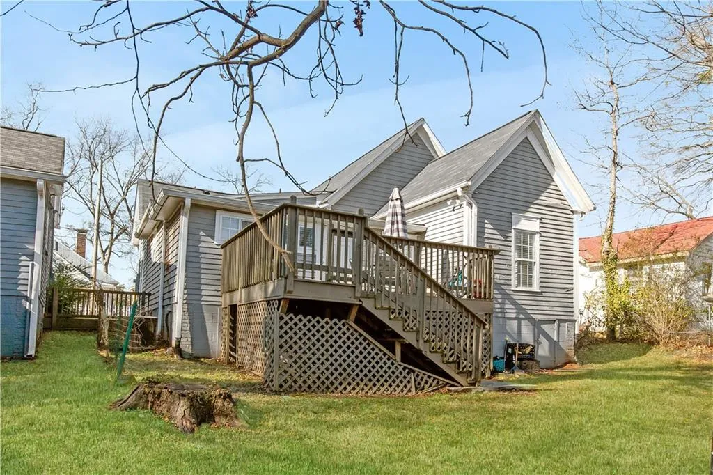 Rear view of property featuring a wooden deck, a lawn, and central AC