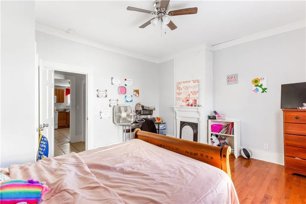Bedroom with ornamental molding, light wood-type flooring, and ceiling fan