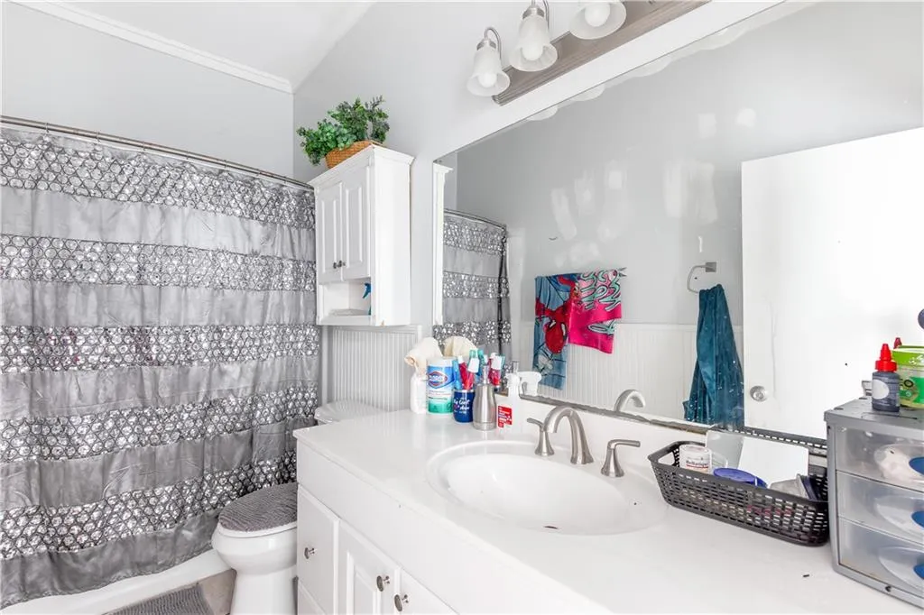Bathroom with ornamental molding, toilet, and vanity