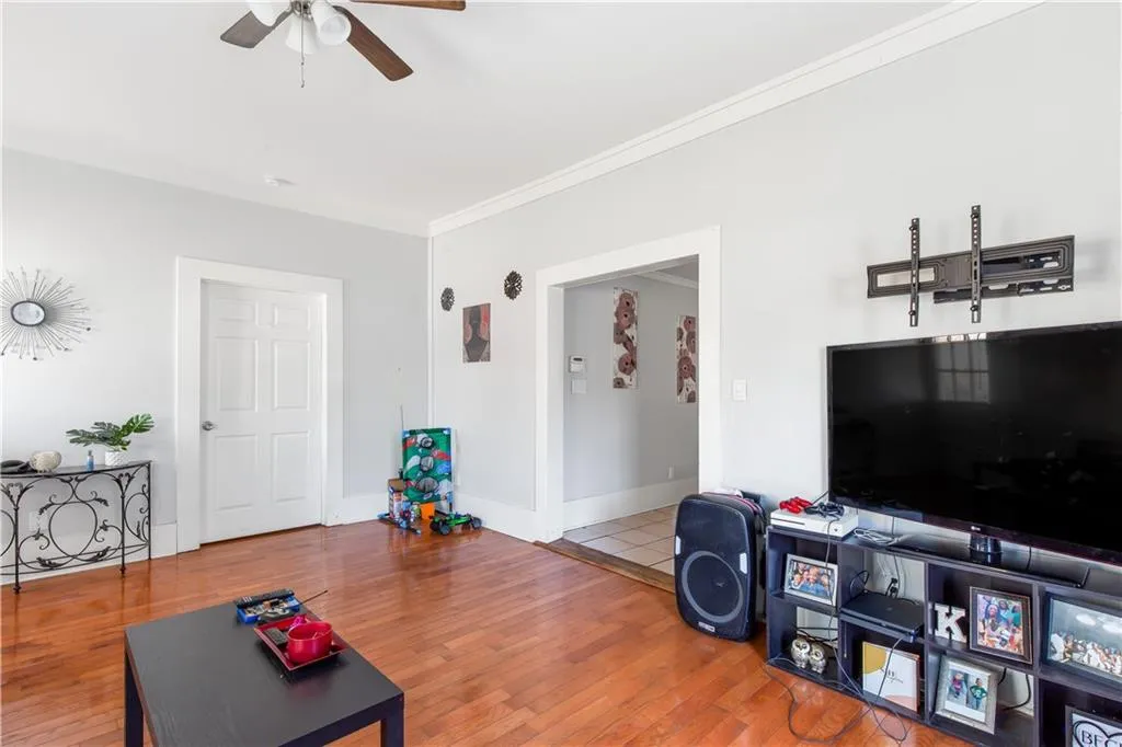 Living room with ornamental molding, light hardwood / wood-style flooring, and ceiling fan