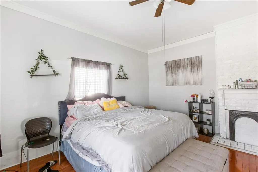 Bedroom featuring light hardwood / wood-style flooring, ornamental molding, a fireplace, and ceiling fan