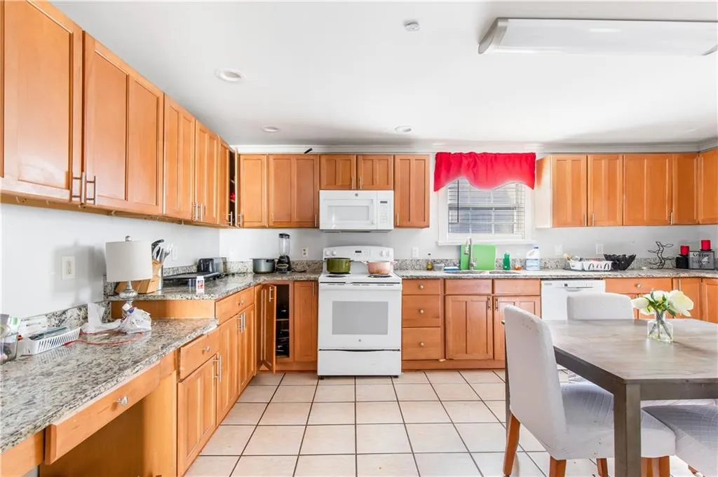 Kitchen featuring light tile floors, light stone countertops, white appliances, beverage cooler, and sink