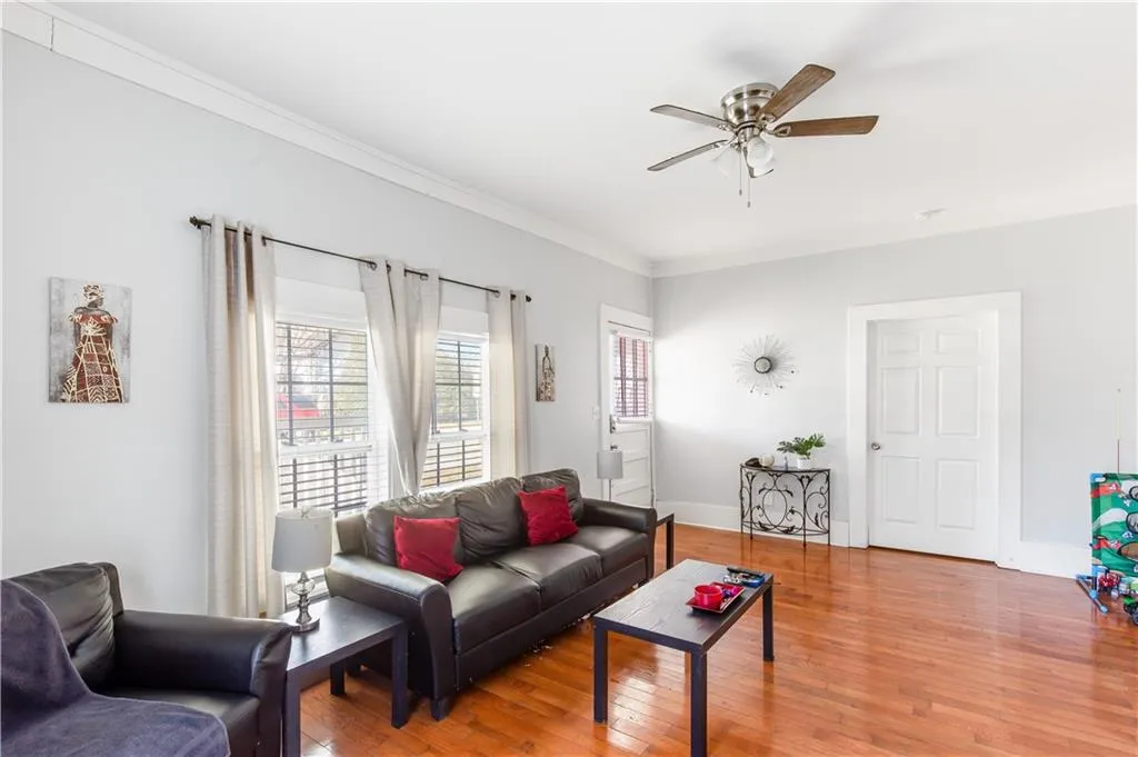 Living room with light hardwood / wood-style flooring, crown molding, and ceiling fan
