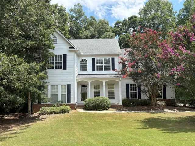 Two-story residence featuring a white siding exterior, dark window shutters, and an arched entry above the front door