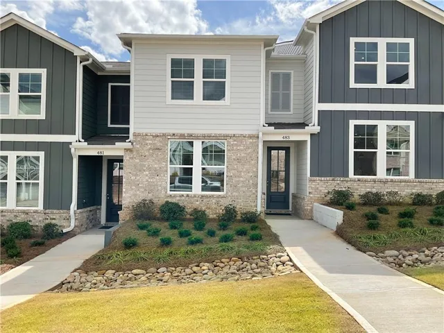 View of front of house with board and batten siding, brick siding, and a front yard