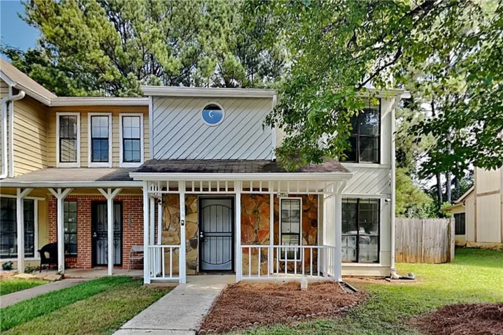 Stone veneer and siding exterior with a white porch railing, a partial front porch, and a second-story round window
