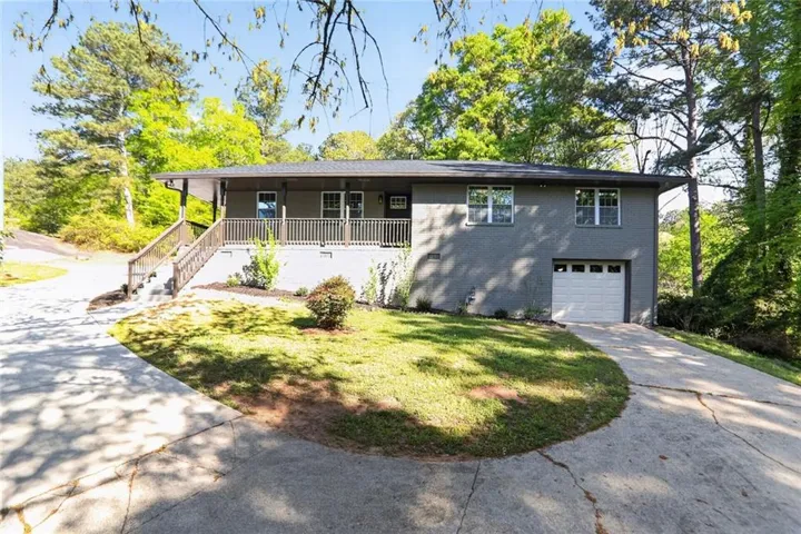 Front of home with garage and more parking to the left and in the rear of the home