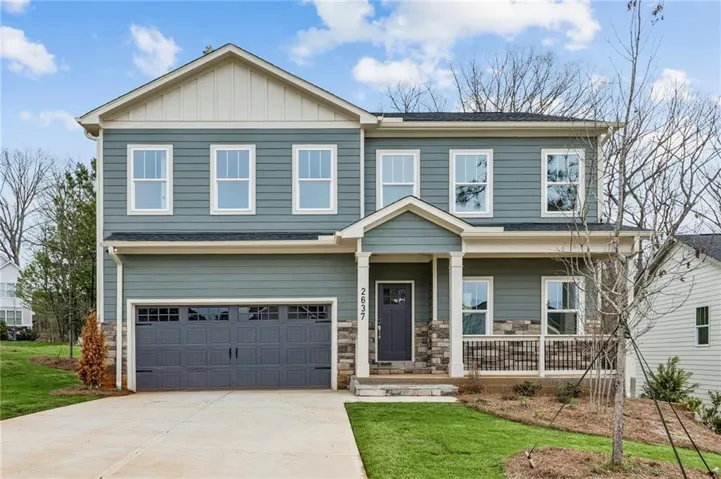 View of front of home with a porch, driveway, board and batten siding, a front lawn, and a garage