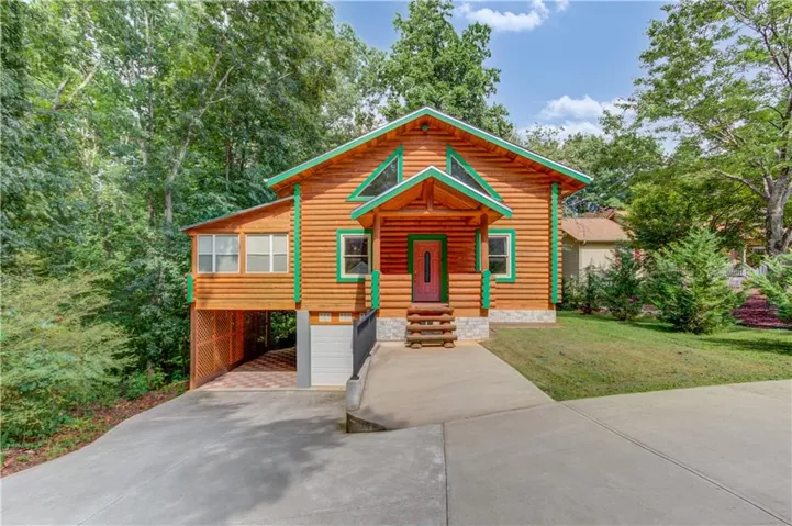Log-sided exterior with green trim accents and a covered front porch featuring rustic log steps