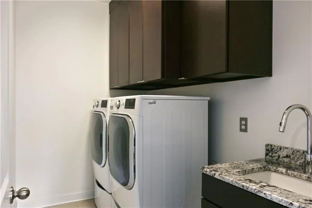Laundry room with washer/dryer, sink and custom cabinets.
