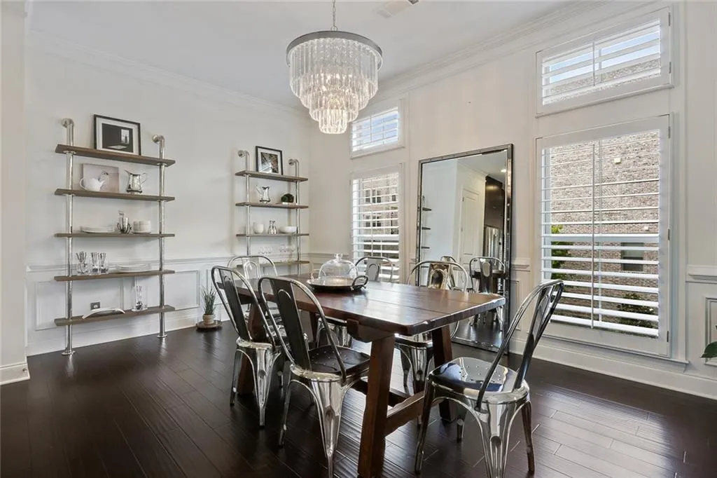 Dining area with crown molding, an inviting chandelier, and hardwood flooring.