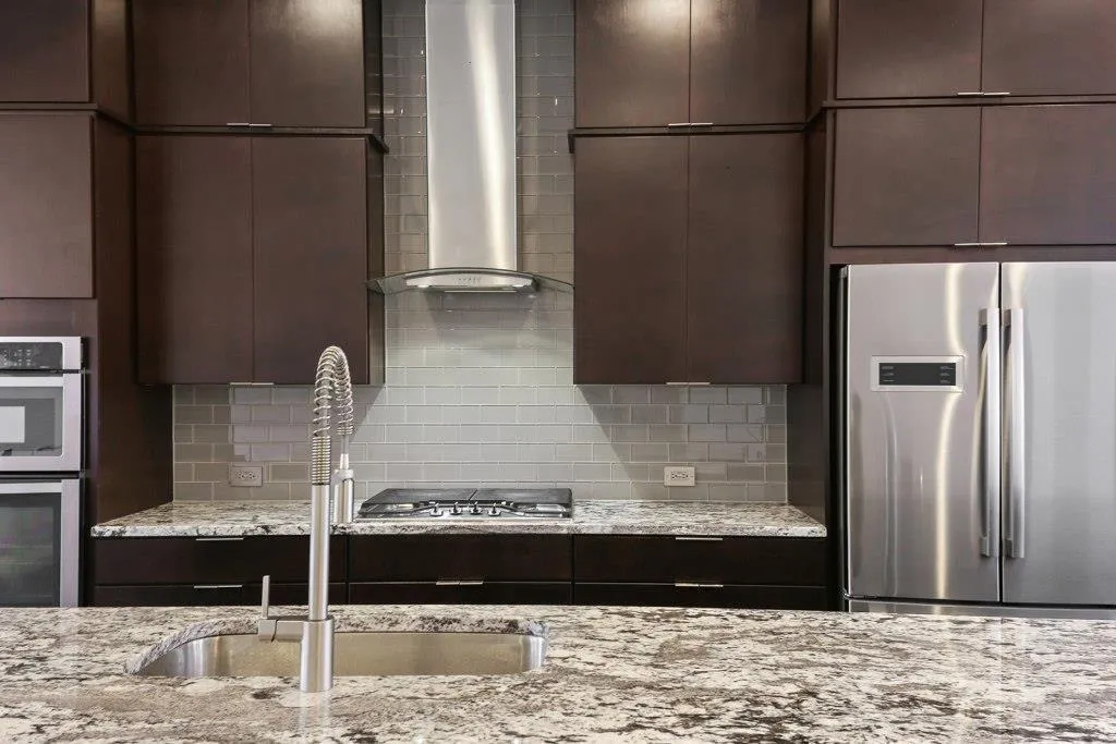 Kitchen with wall chimney exhaust and gas range.