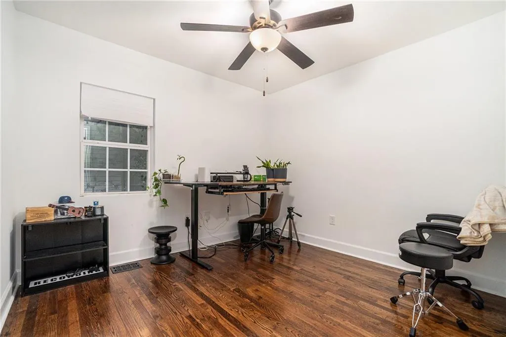 Office area with dark wood-style floors and a ceiling fan