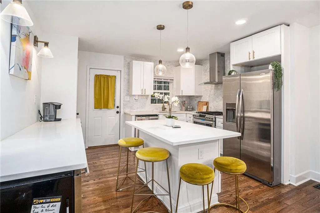 Kitchen with appliances with stainless steel finishes, white cabinets, wall chimney exhaust hood, tasteful backsplash, and recessed lighting