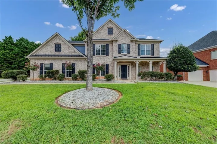 Brick exterior with gabled roof lines, covered front porch with columns, and a two-car garage