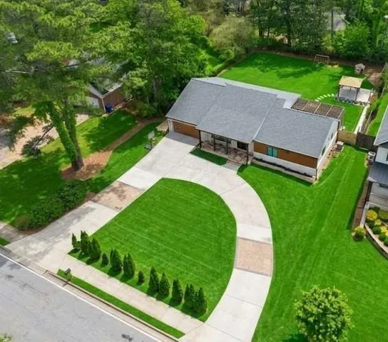 Expansive lawn with mature trees and a curved concrete driveway