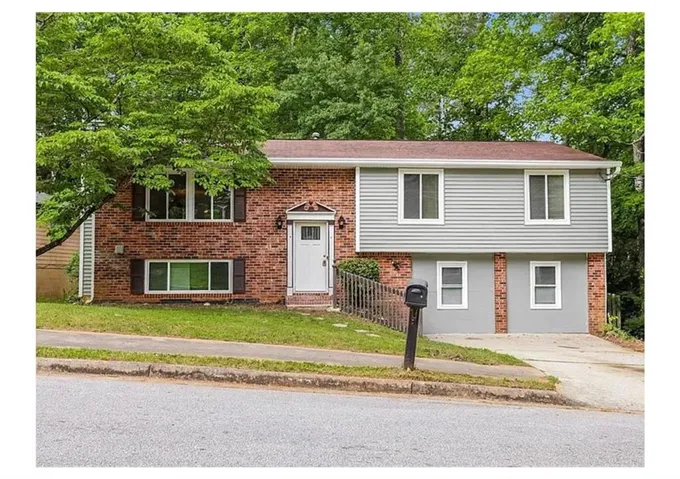 Brick and siding exterior featuring white trim windows and a white front entry door