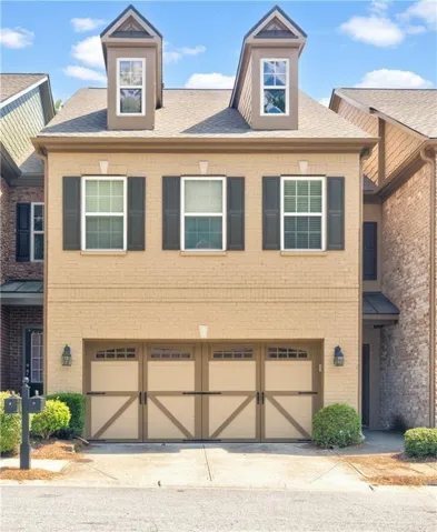 Brick exterior featuring dormer windows, dark shutters, and a two-car garage with carriage-style doors