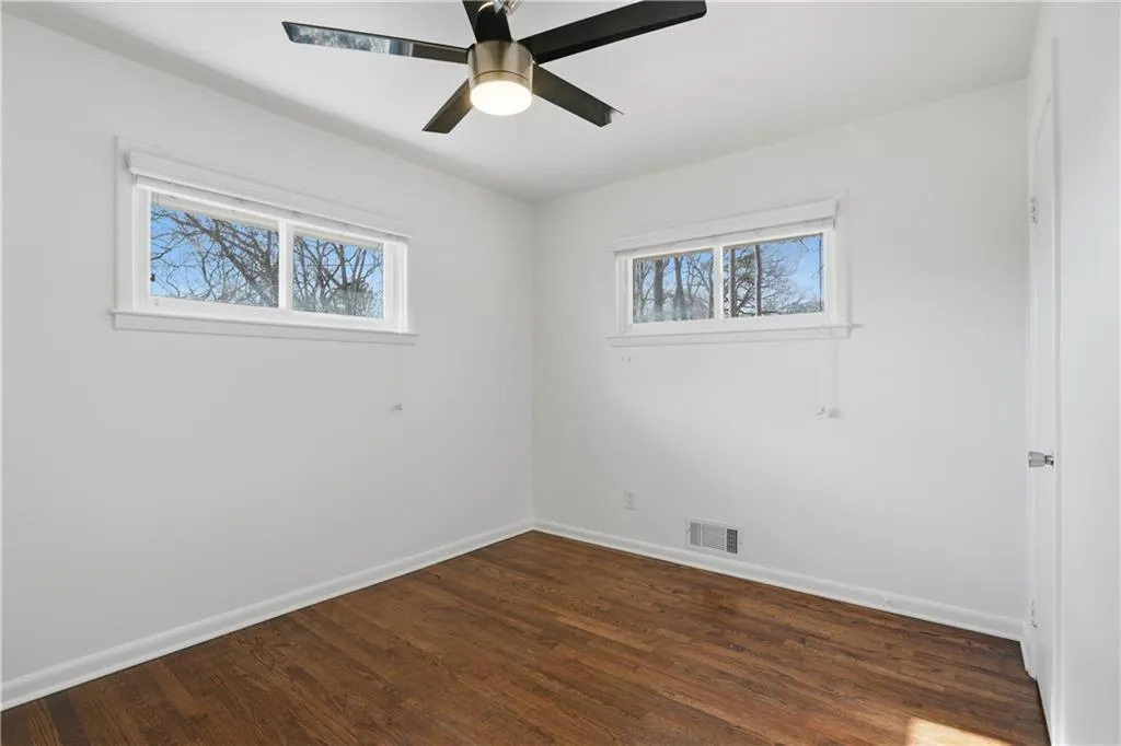 Empty room with dark wood-style flooring and a ceiling fan