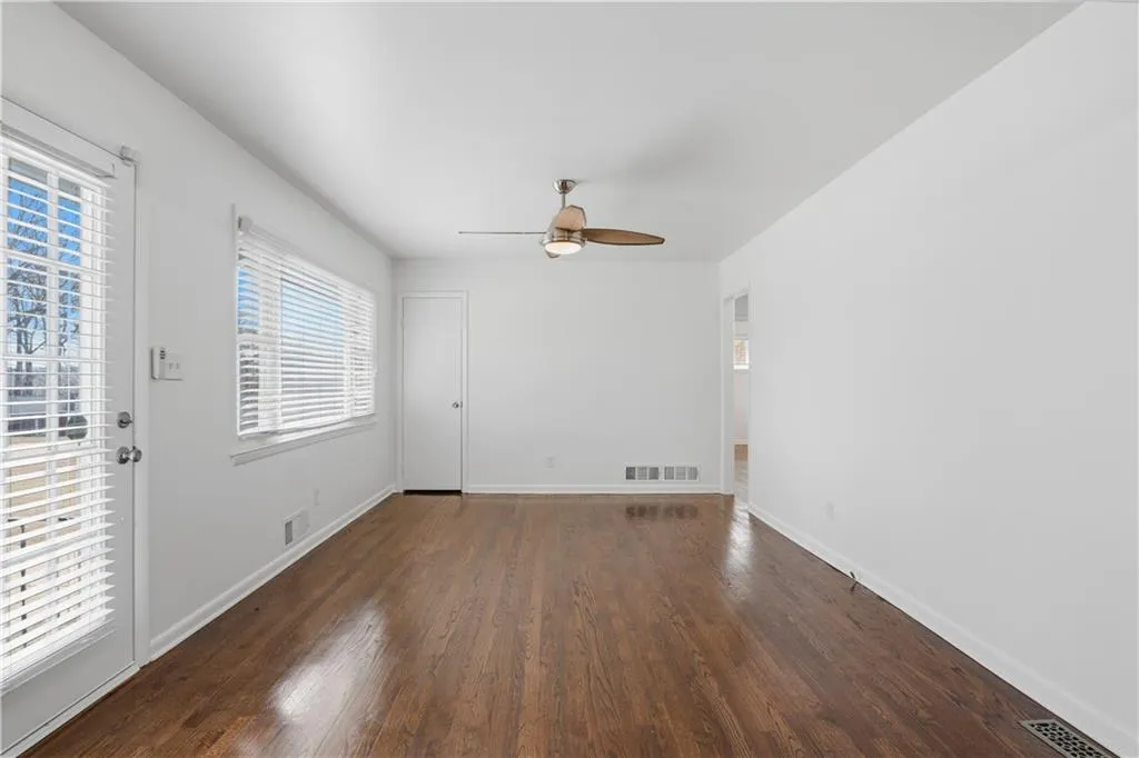 Unfurnished room featuring dark wood-style flooring and a ceiling fan