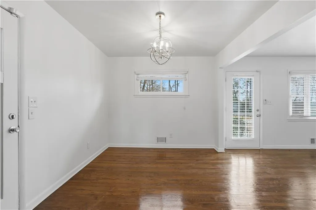 Unfurnished dining area with suspended lighting and dark wood-style flooring