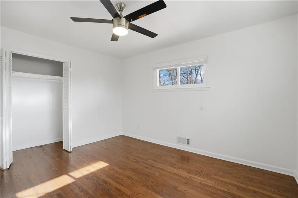 Unfurnished bedroom with dark wood-style flooring, a ceiling fan, and a closet
