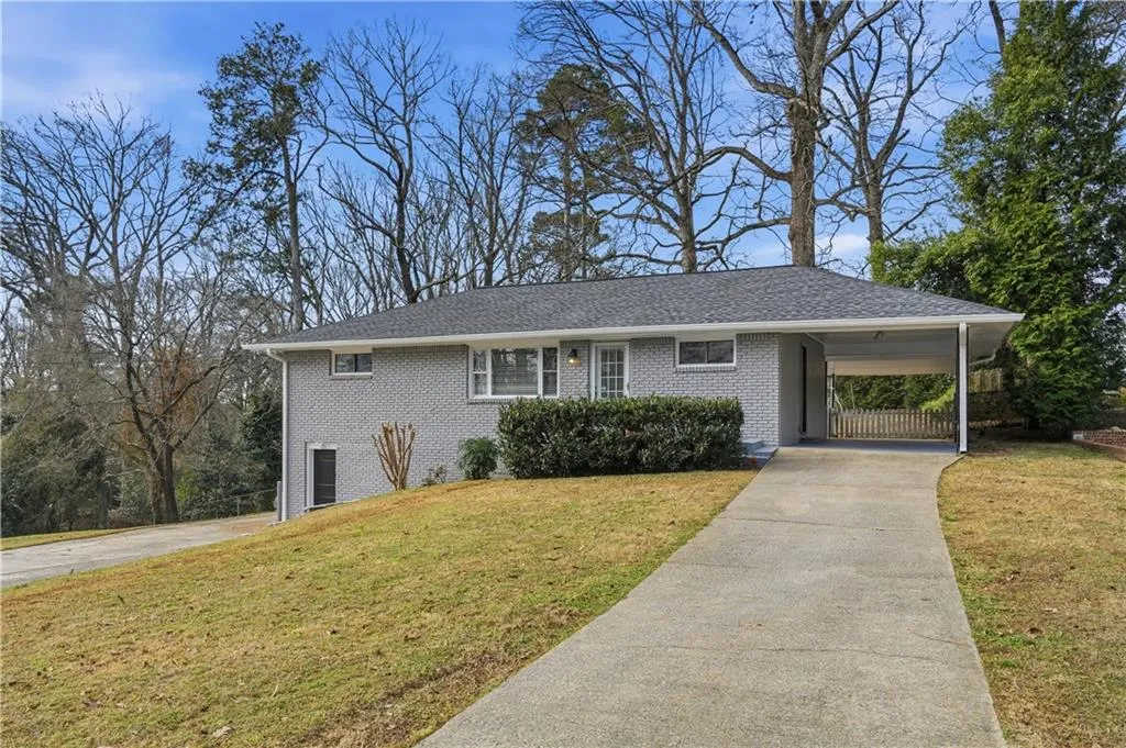 View of front facade with a front yard, driveway, brick siding, and a carport