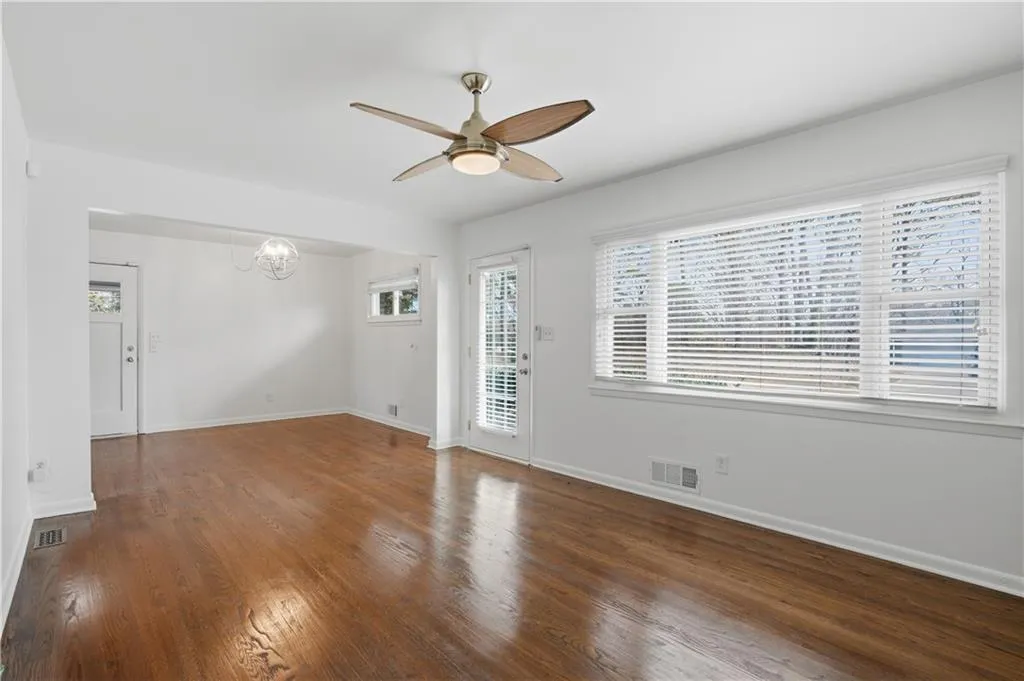 Unfurnished room with ceiling fan, suspended lighting, and dark wood-style flooring