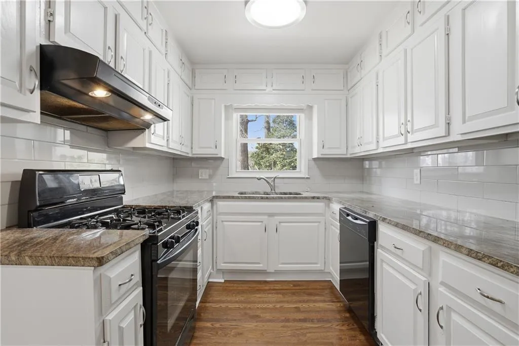 Kitchen featuring black appliances, white cabinetry, dark wood finished floors, and backsplash
