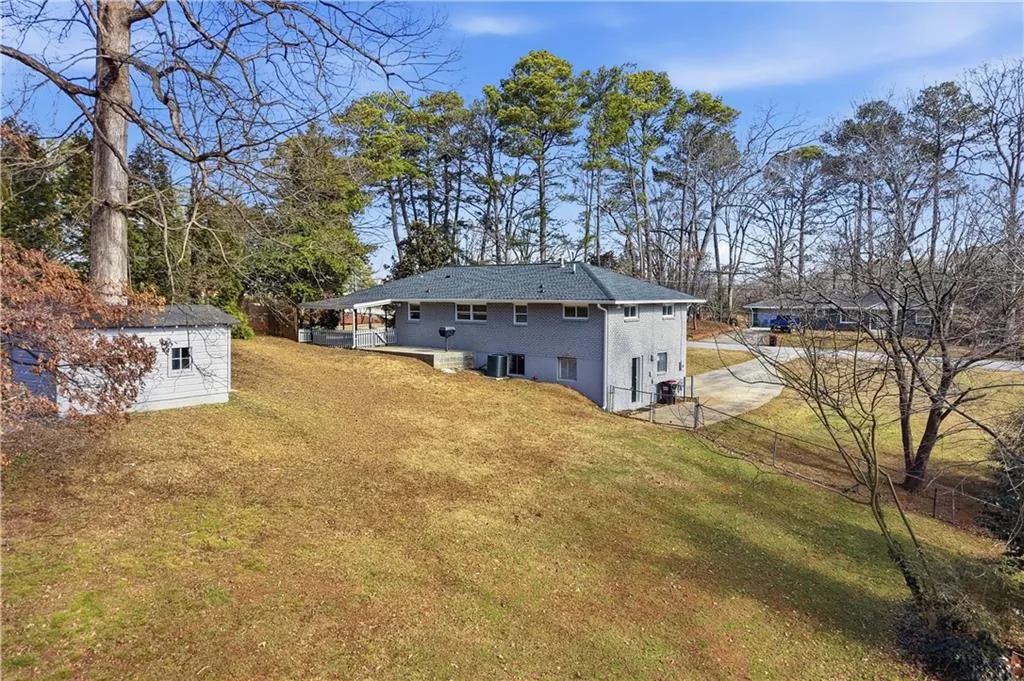 Back of house with an outdoor structure, a lawn, and a patio area