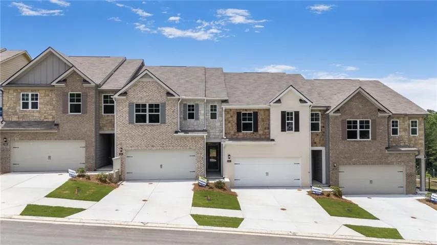 Brick and stone facade, gabled rooflines, two-car garages, concrete driveways, and mature landscaping