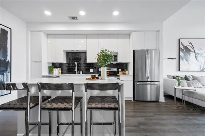 Kitchen featuring dark hardwood / wood-style flooring, tasteful backsplash, white cabinets, and stainless steel appliances