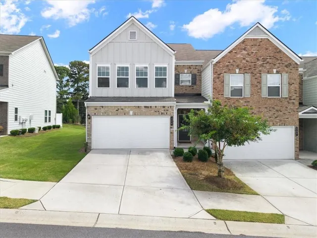 Brick and siding exterior with multiple gabled roofs, two integrated garages, and a paved driveway