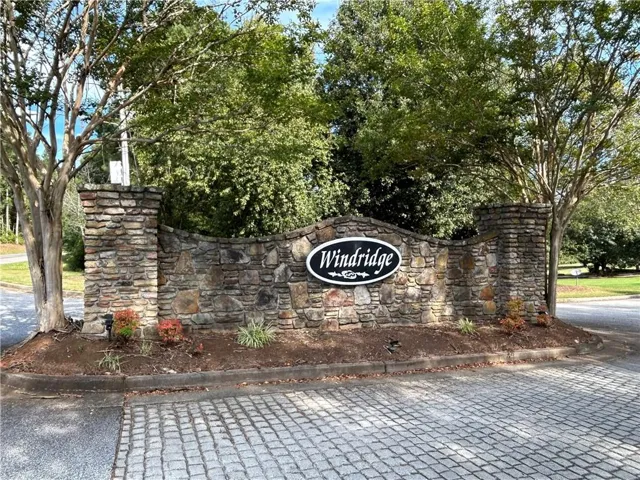 Stone entrance monument with integrated signage, mature trees, and landscaping