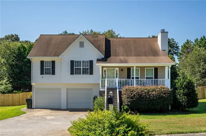 Welcoming exterior featuring classic curb appeal, a covered front porch, mature landscaping, and a two-car garage.
