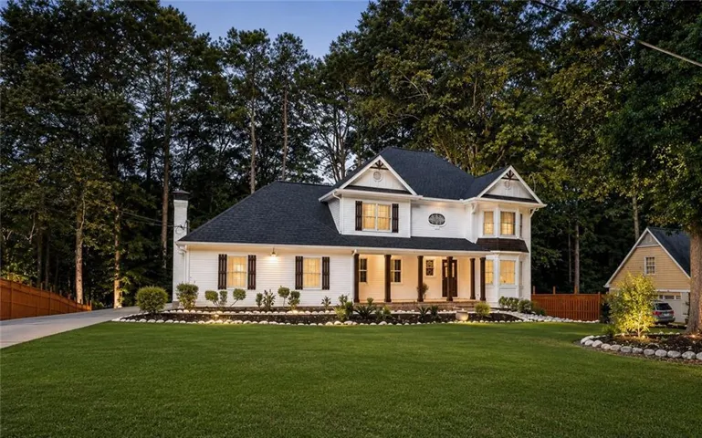 Elegant two-story residence featuring a white exterior, dark shingle roof, and a welcoming front porch with classic columns