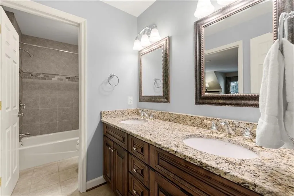 Bathroom featuring tile flooring, tiled shower / bath, and dual bowl vanity
