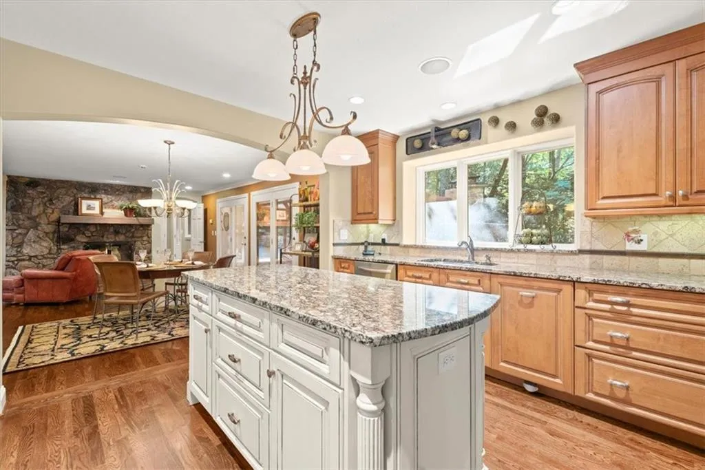 Kitchen featuring hanging light fixtures, a fireplace, light wood-type flooring, sink, and tasteful backsplash
