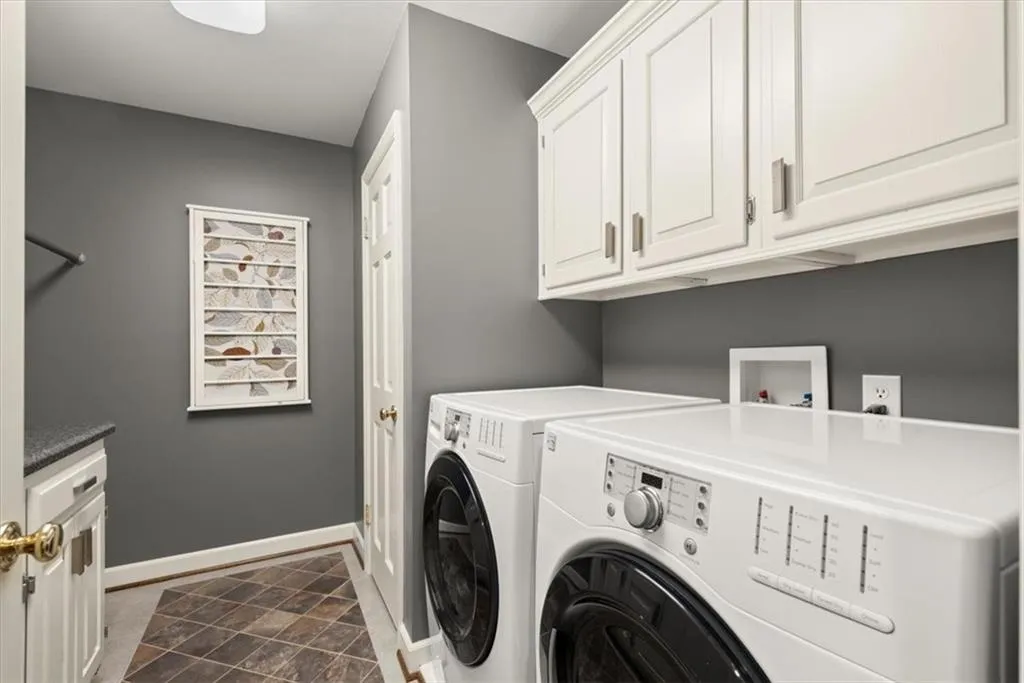 Washroom with tile floors, washing machine and dryer, cabinets, and washer hookup