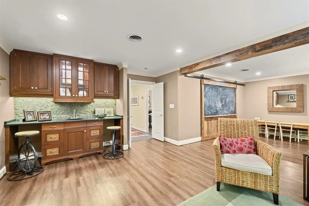Kitchen featuring a barn door, crown molding, light wood-type flooring, and backsplash