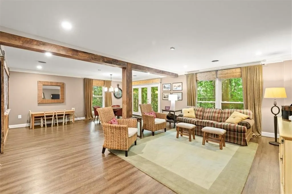 Living room with a notable chandelier, beam ceiling, and light hardwood / wood-style flooring