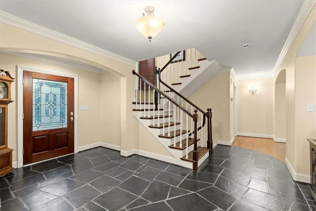 Foyer entrance featuring dark tile flooring and ornamental molding