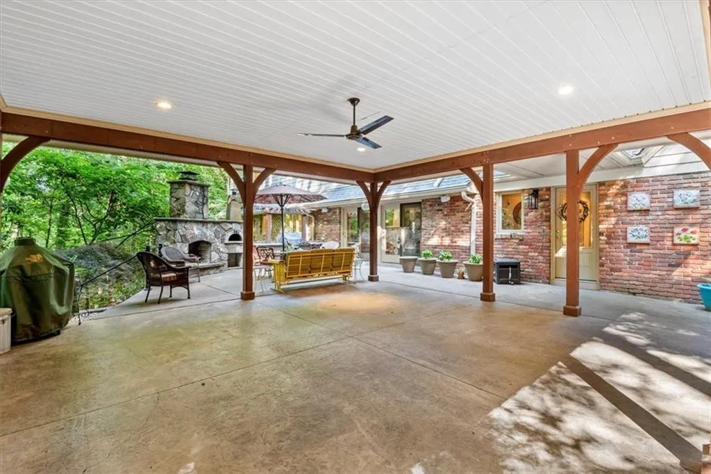 View of terrace with ceiling fan and a fireplace