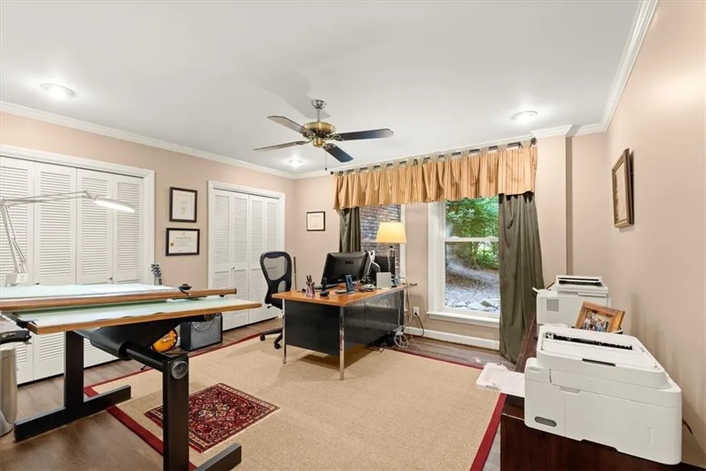 Home office featuring wood-type flooring, ornamental molding, and ceiling fan